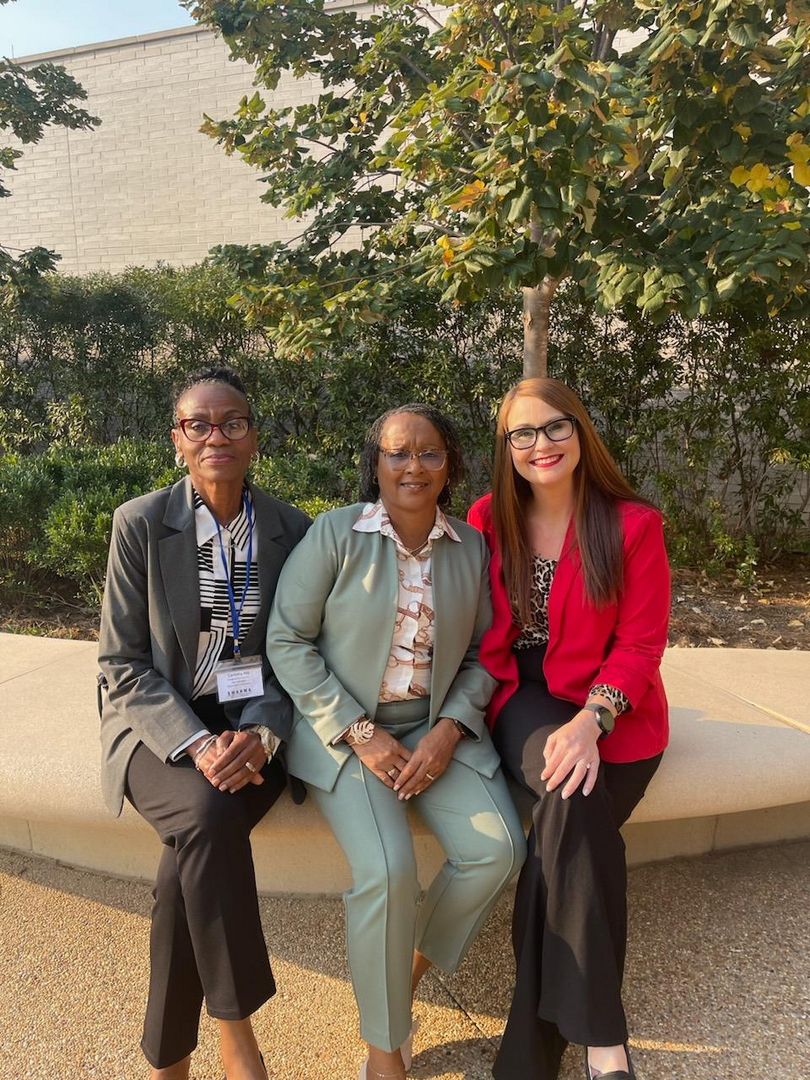 Three professional women sitting outdoors at a brick building