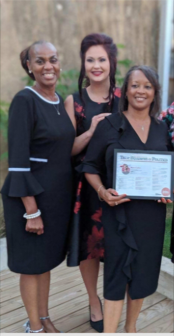 Three women in professional attire receiving a certificate award