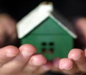 Small house model held in hands representing affordable housing