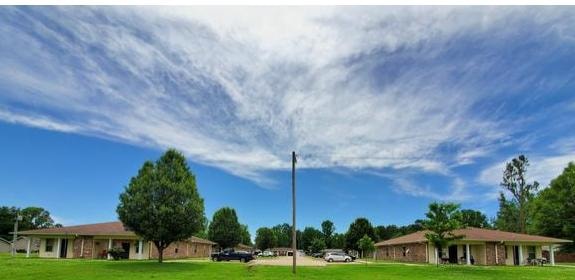 Corning Senior Apartments in Corning, Arkansas — single-story brick buildings under a wide blue sky with green trees