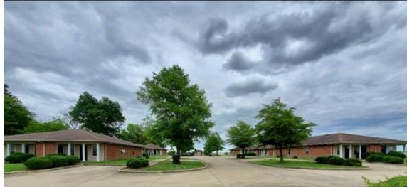 Joiner Village Apartments in Joiner, Arkansas — brick residential buildings with mature trees