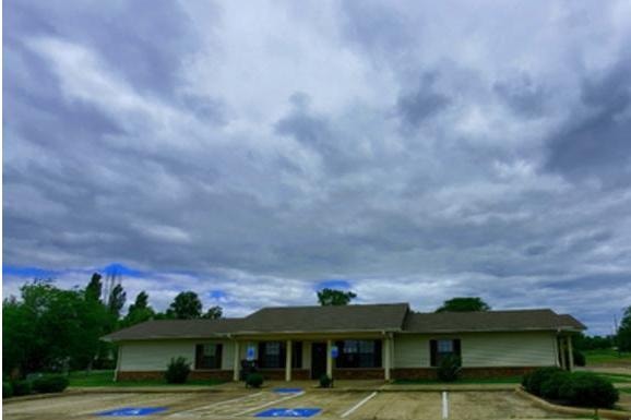 Turrell Place Apartments in Turrell, Arkansas — single-story building with parking lot under dramatic cloudy sky